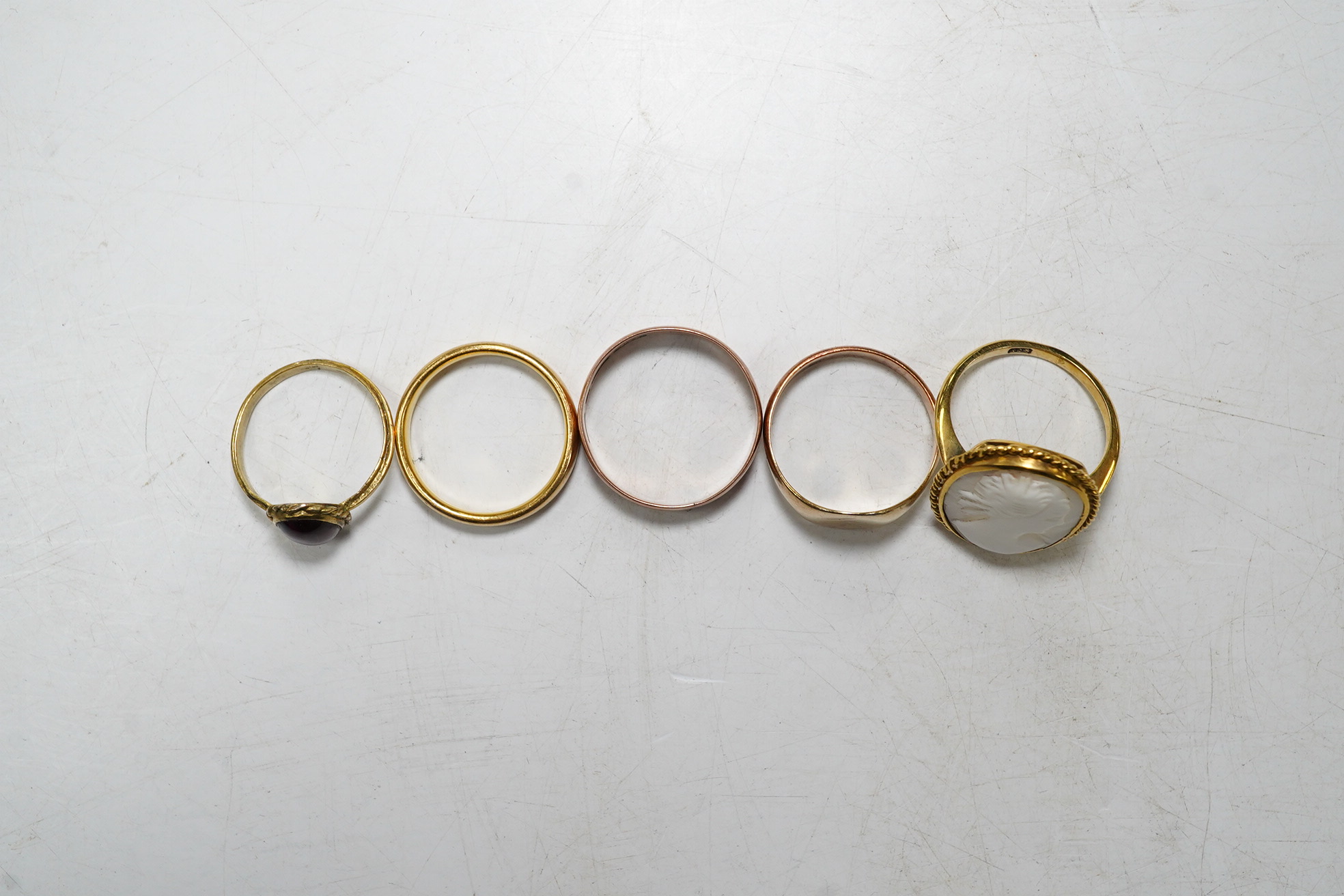 Five assorted rings: a 22ct gold band, size L, 4.2 grams, a 9ct rose gold band, size O, 2.1 grams, a 9ct gold signet ring, size M, 2.1 grams, a red cabochon set yellow metal ring, size I, gross 1.4 grams and a cameo set